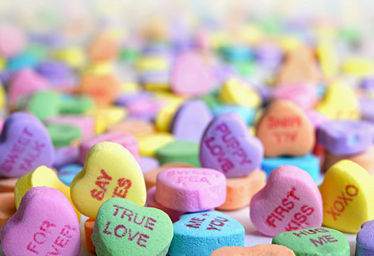 Colorful conversation heart candies scattered on a white surface for Valentine's Day